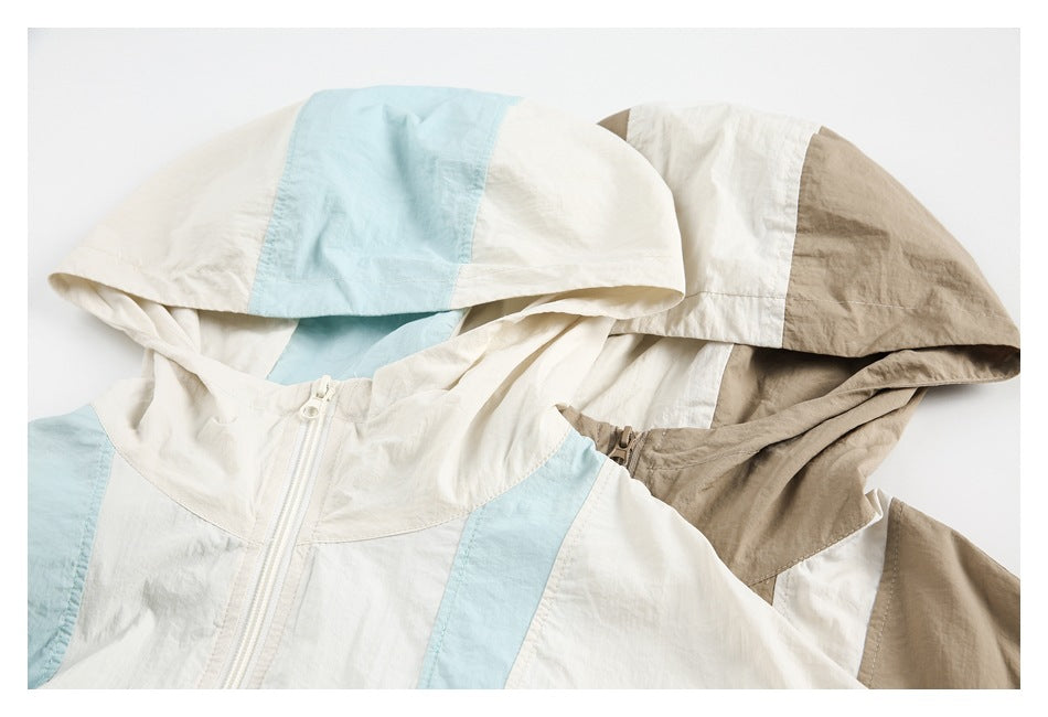 Two hooded zip jackets overlap: one cream with pale blue panels and one cream with taupe panels.