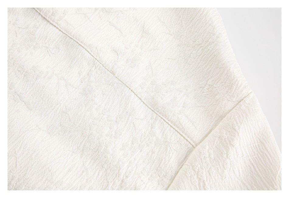 Close-up of ivory fabric showing raised floral texture and a diagonal stitched seam.