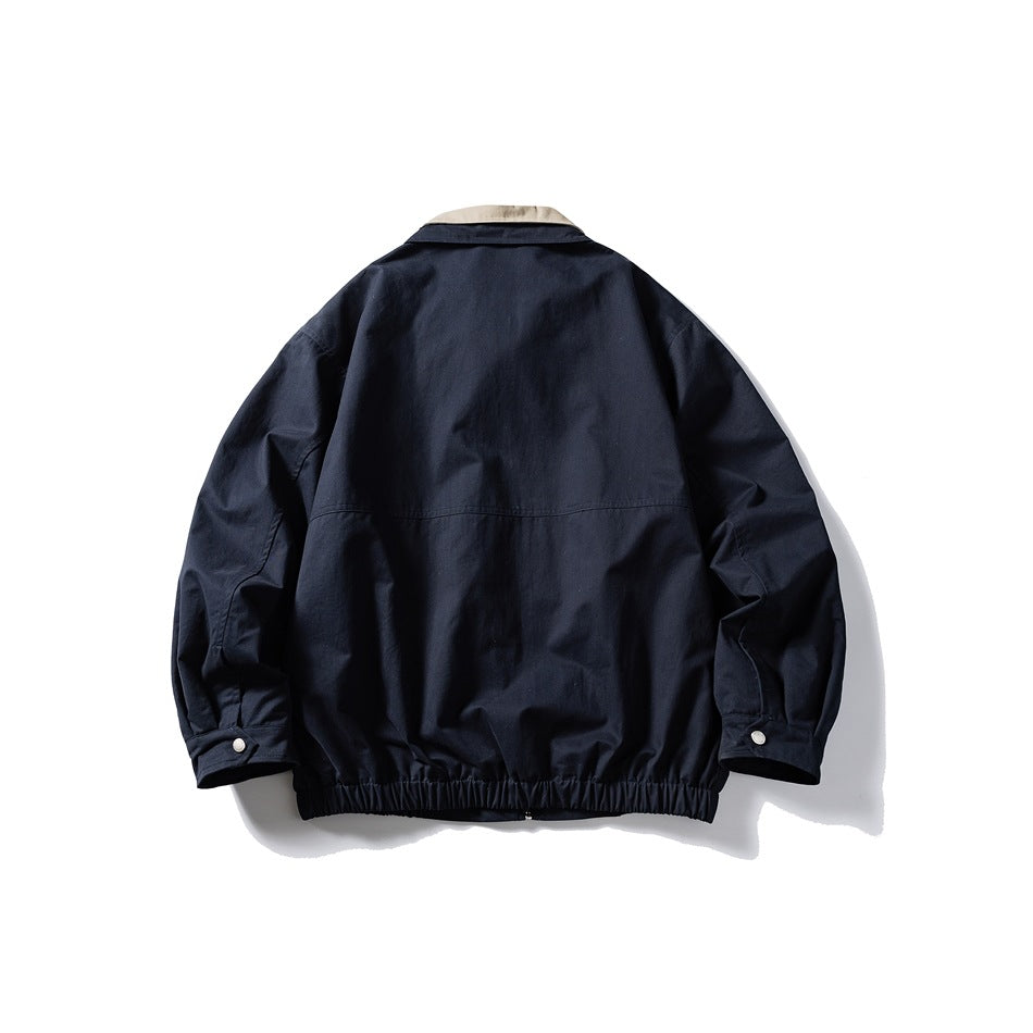 Back view of navy jacket with beige collar edge, back yoke seam, snap cuffs and elastic hem