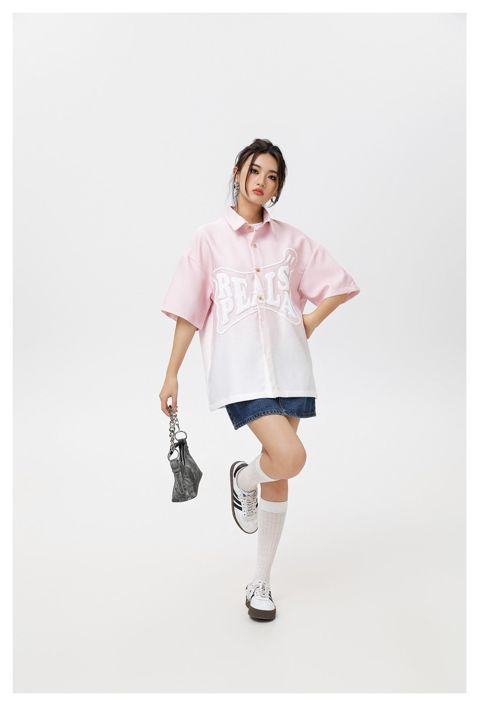 Model wearing an oversized pink-to-white short-sleeve button-up shirt with large white PEALS lettering.
