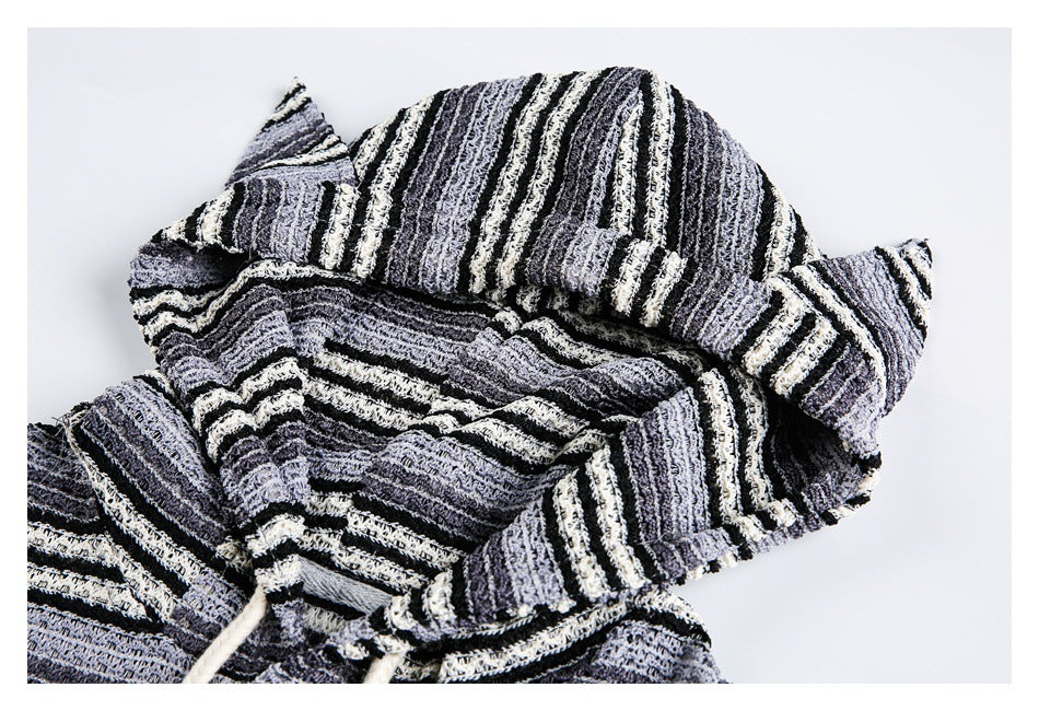 Close-up of a gray, black, and cream striped hood with pointed side details on a matching pullover.