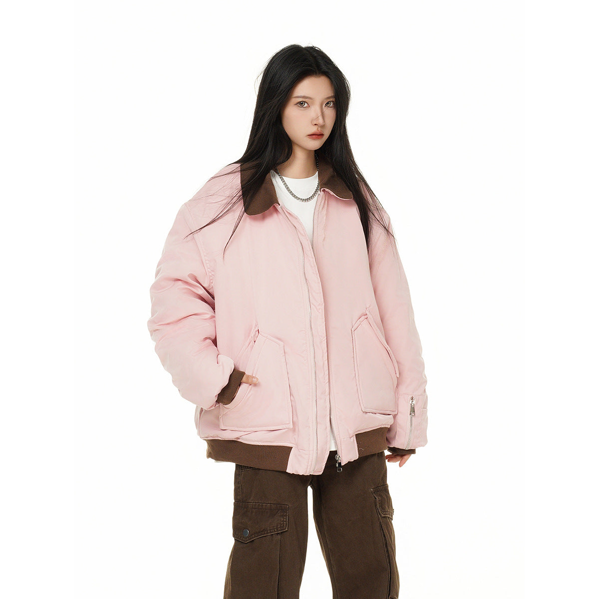 Model in a pale pink oversized jacket with a dark brown collar, ribbed trim and large pockets, with brown cargo pants.