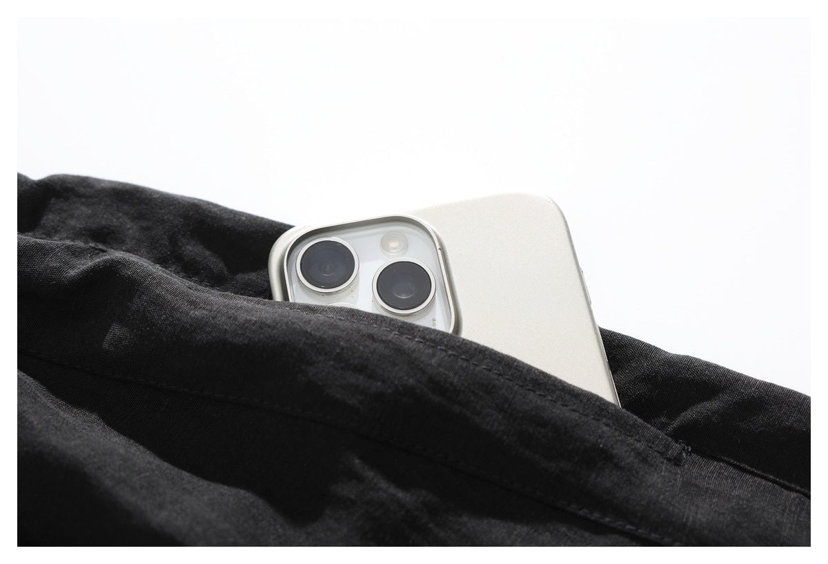 Close-up of a black garment pocket holding a silver smartphone, showing the pocket opening and stitching.