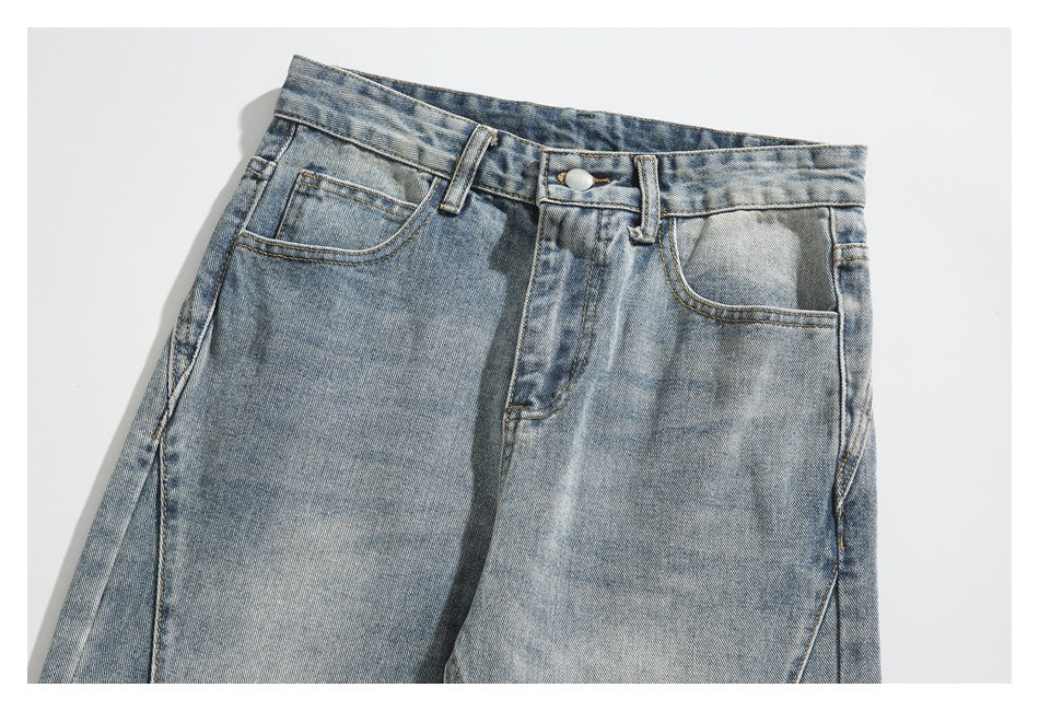 Close-up of the front waistband, button, and pockets on light-wash blue jeans.