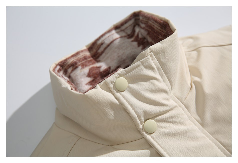 Close-up of the ivory jacket's high collar, snap-button placket and brown patterned inner lining.