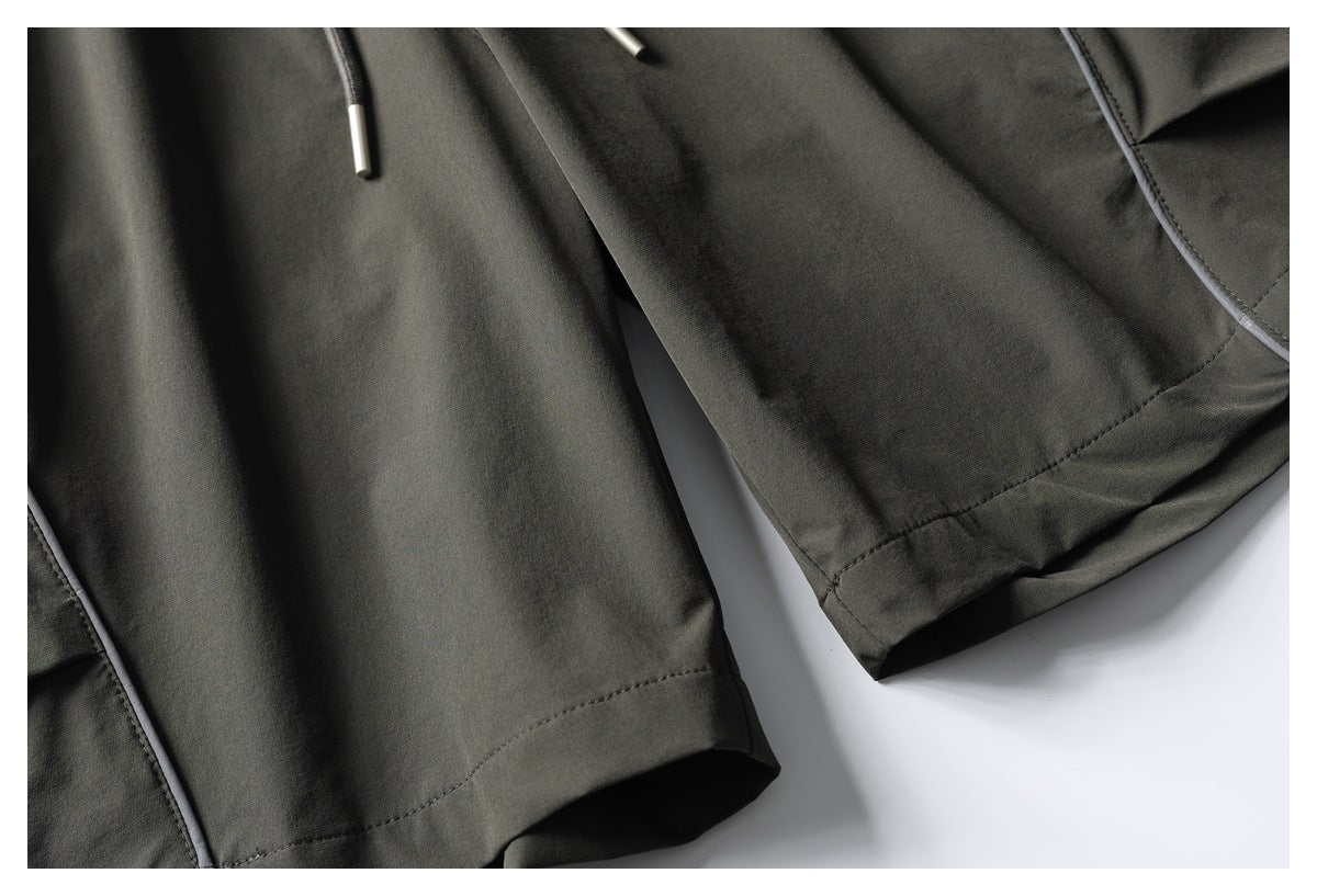 Close-up of dark charcoal garment hems, stitching, and light-colored edge piping.