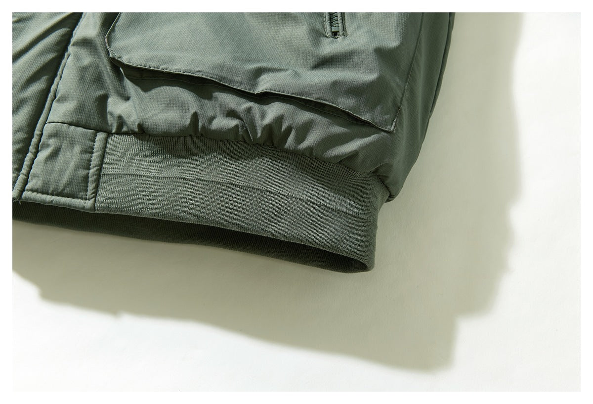 Close-up of the sage green jacket's ribbed hem and lower edge of a pocket.