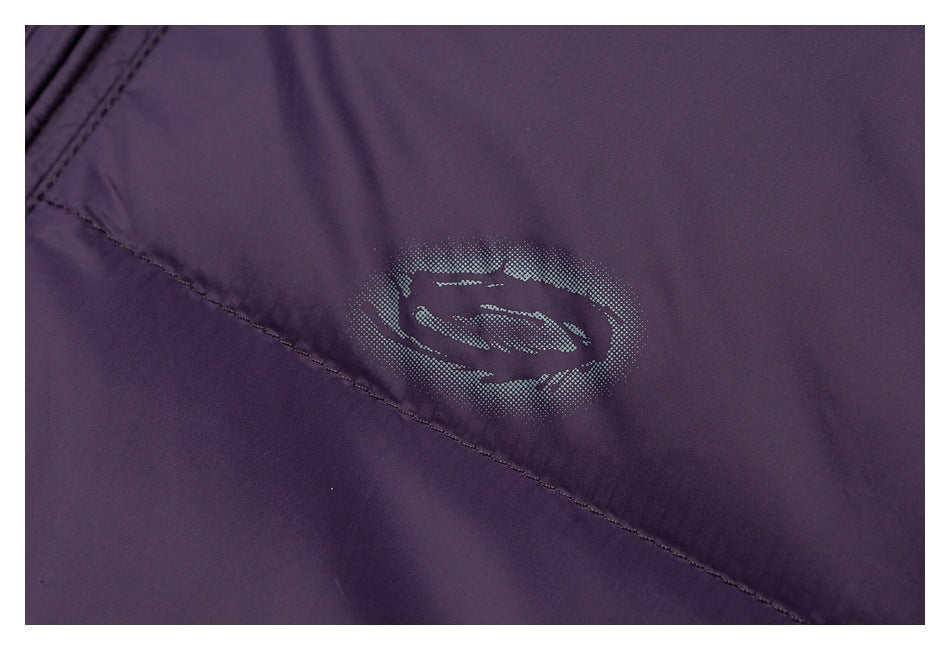 Close-up of a small silver-gray emblem printed on purple jacket fabric beside a diagonal seam.