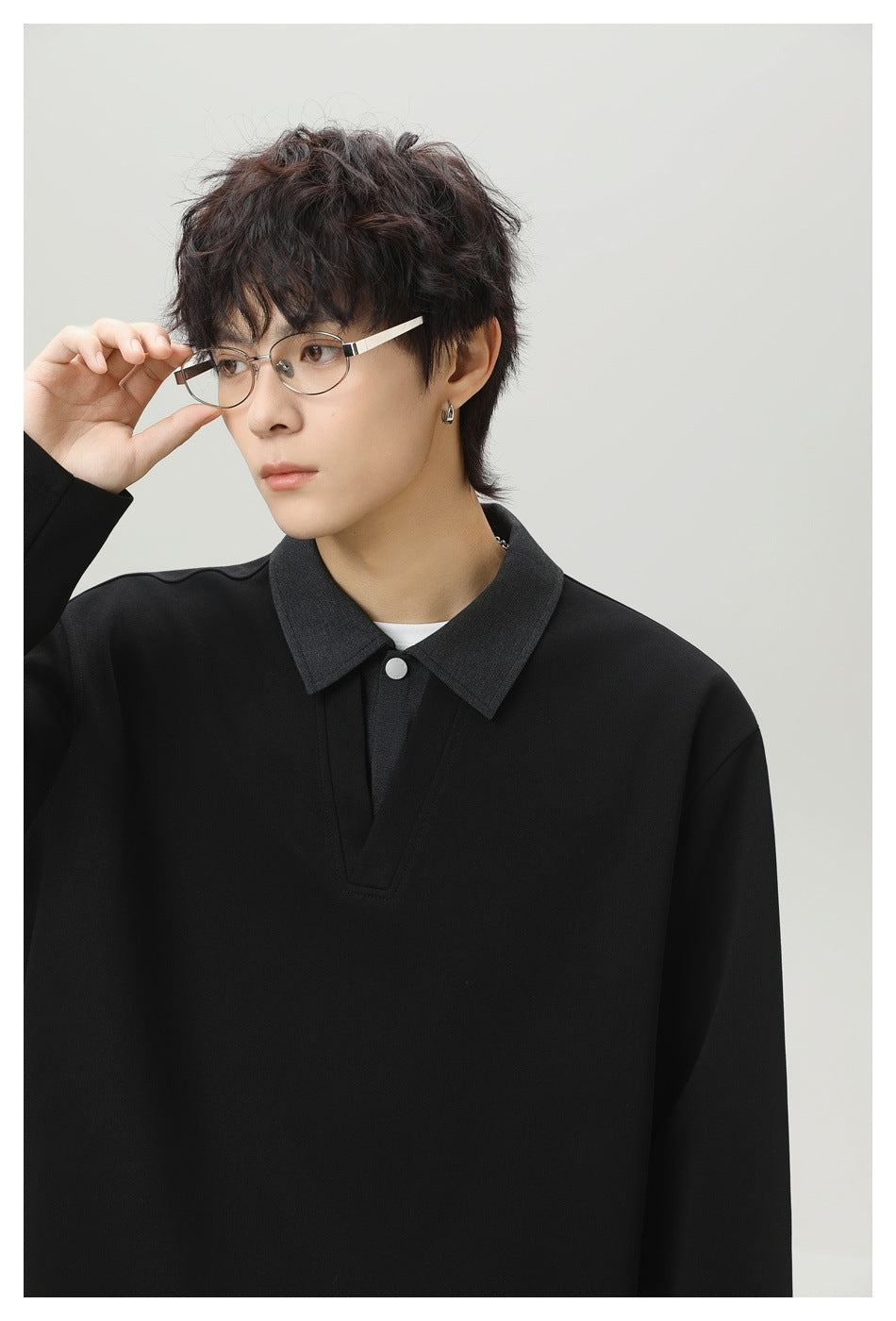 Close-up of a model wearing a black top with a charcoal pointed collar, silver button, and V-shaped placket.