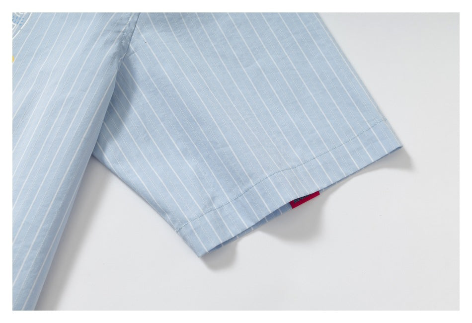 Close-up of the hem of a light blue pinstriped sleeve, showing the seam and a small edge tag.