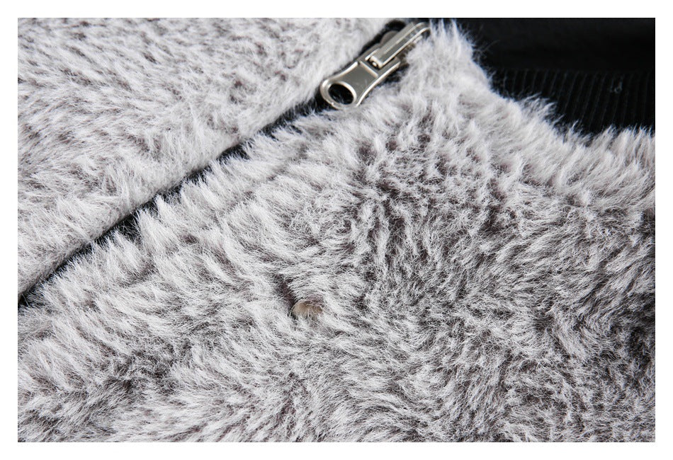 Close-up of gray and white shaggy garment pile with a silver zipper pull and black ribbed fabric.