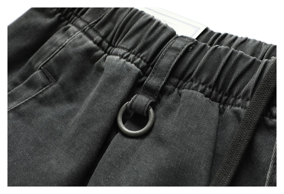 Close-up of charcoal shorts showing the gathered elastic waistband, belt loop, and metal D-ring.
