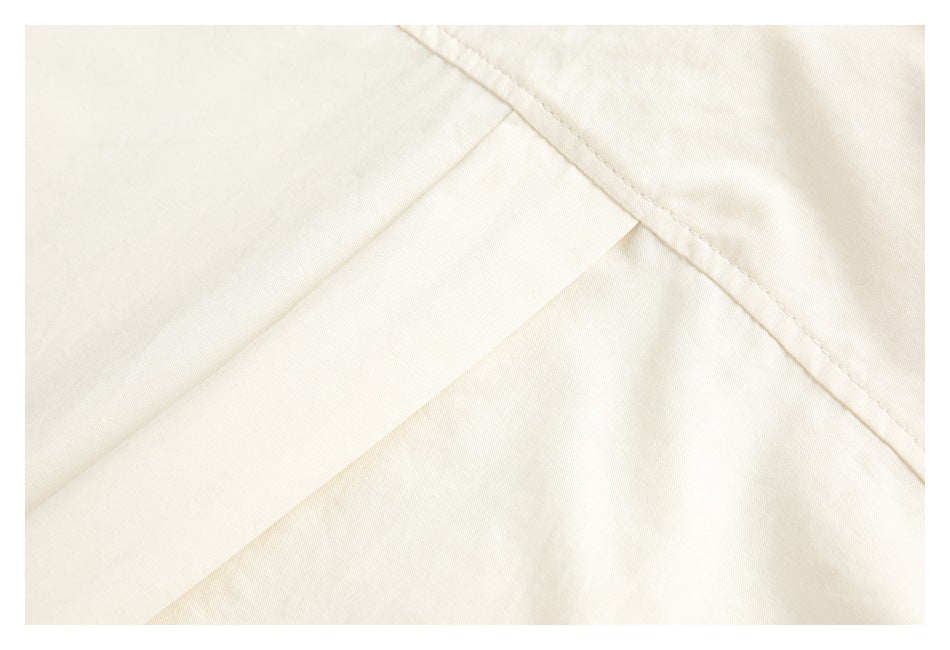 Close-up of ivory fabric showing a diagonal stitched seam and overlapping panel.