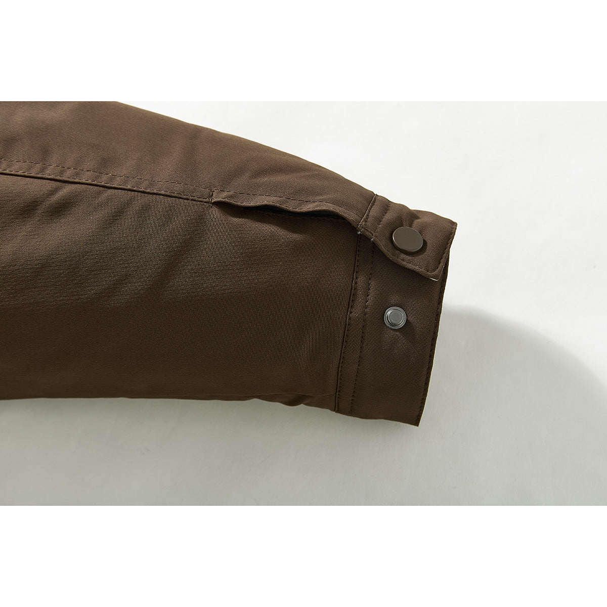Close-up of a brown jacket sleeve cuff with a snap-button tab.