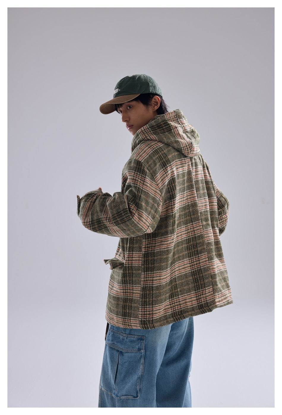 Model seen from behind wearing green plaid hooded jacket with light blue cargo jeans
