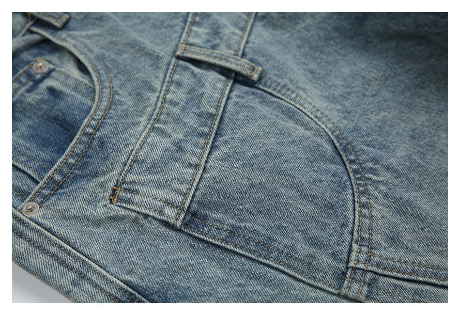 Close-up of a curved front pocket, belt loop, and seams on light blue washed jeans.