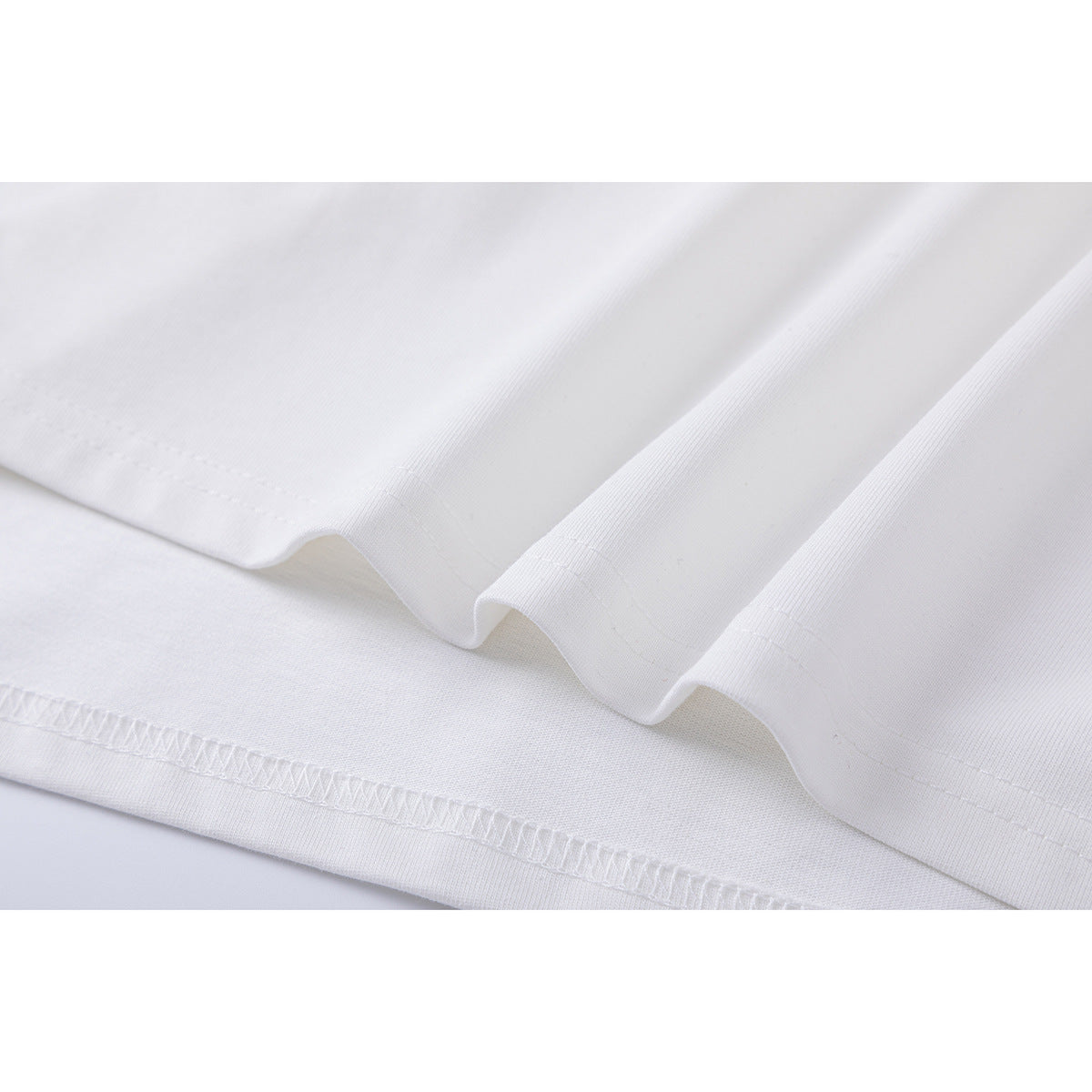 Close-up of the white T-shirt's folded hem and visible stitching.