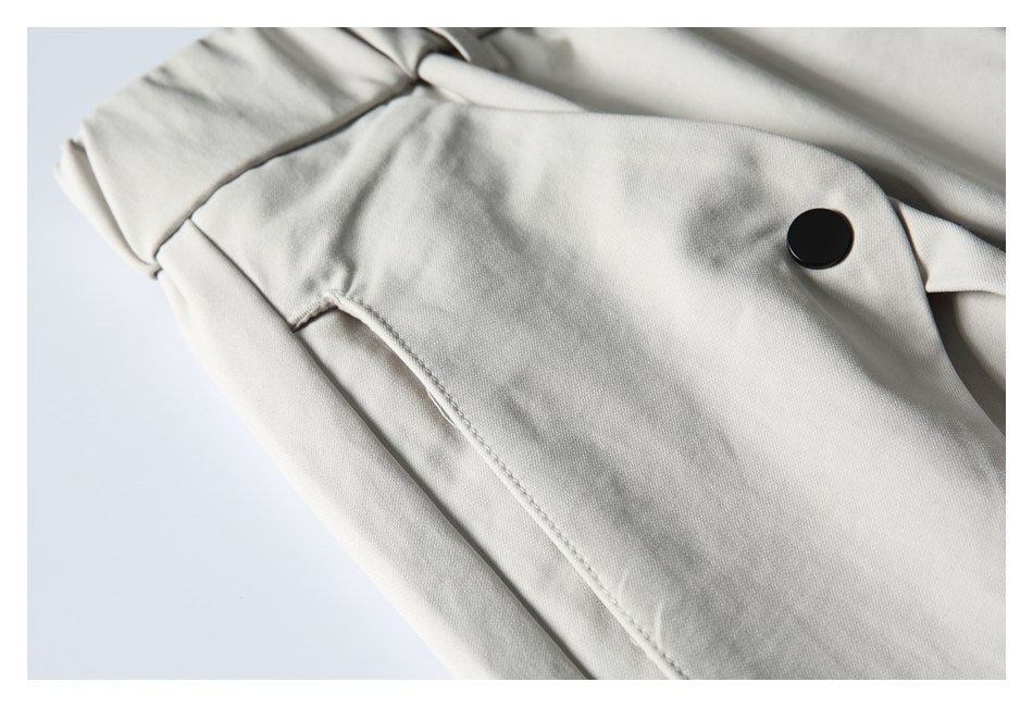 Close-up of a light gray trouser pocket seam and black button.