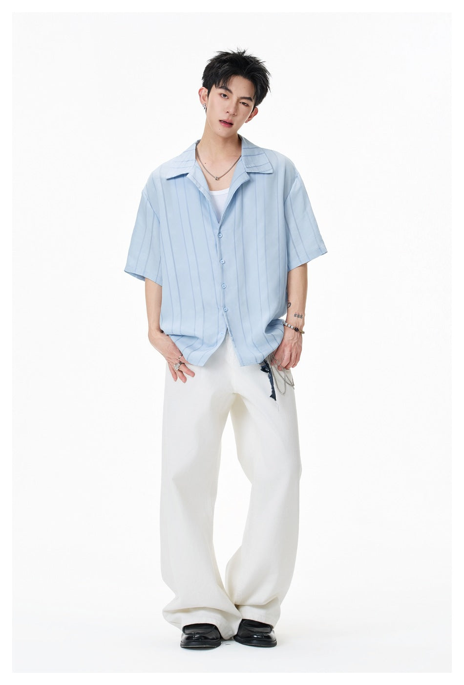 Model wearing light blue striped short-sleeve shirt over a white tank with white wide-leg pants, full-length view
