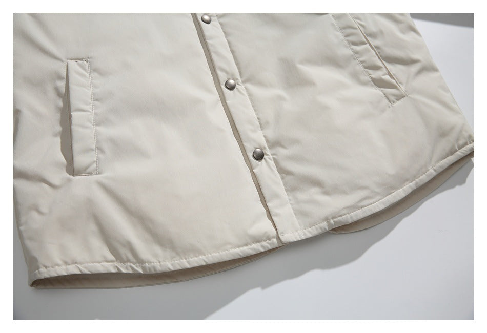 Cropped lower front of an ivory jacket showing snap closures, side pockets, and a curved hem.