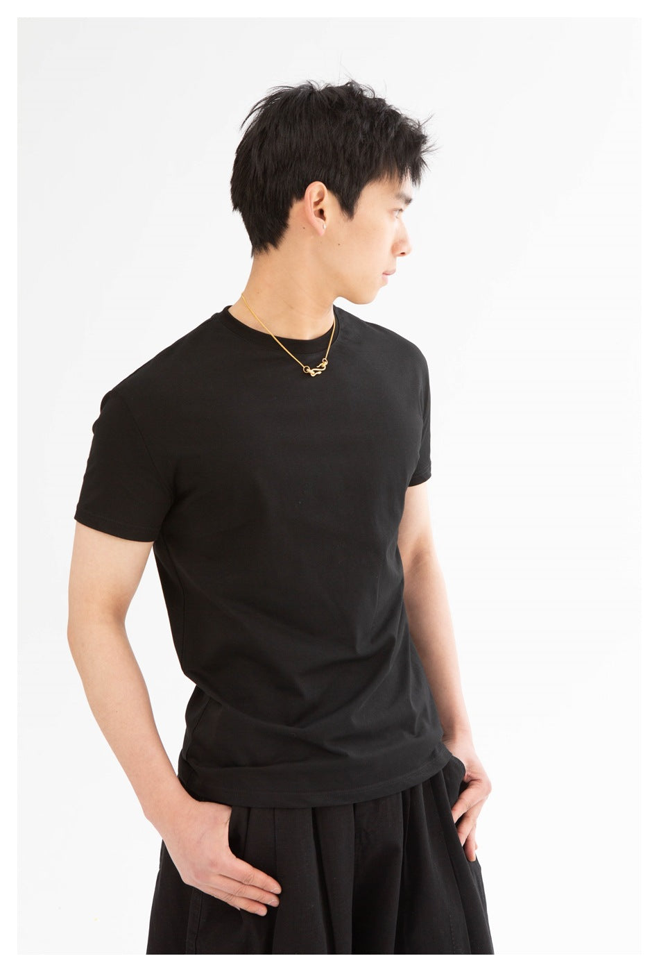 Model wearing a plain black crew-neck T-shirt, shown from the side at a three-quarter angle.