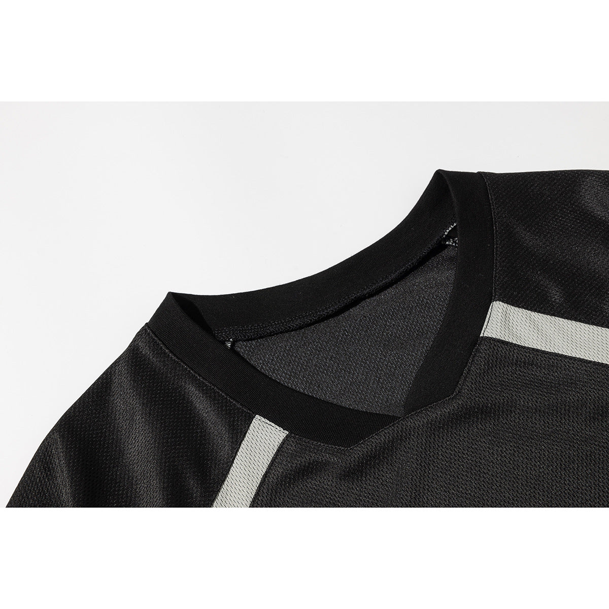 Close-up of a black mesh jersey's V-neck collar and light gray shoulder stripes.