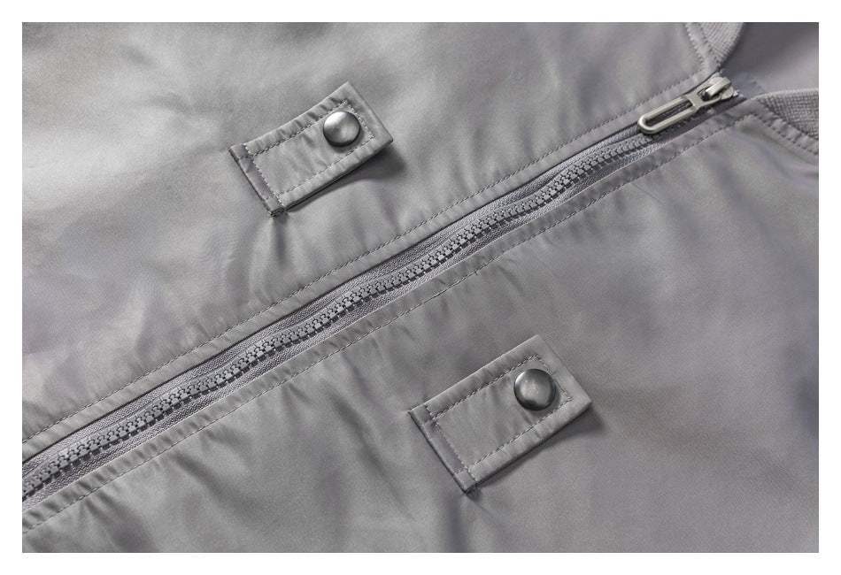 Close-up of a gray jacket’s front zipper and two snap-button tabs.