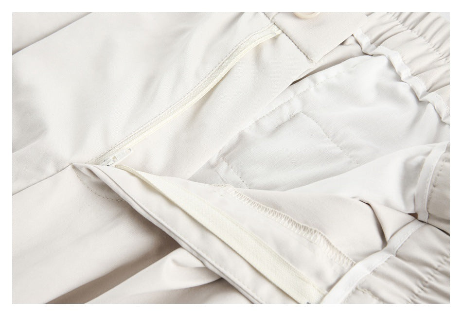 Close-up of off-white trousers showing the front zipper, waistband button, and inner fly construction.