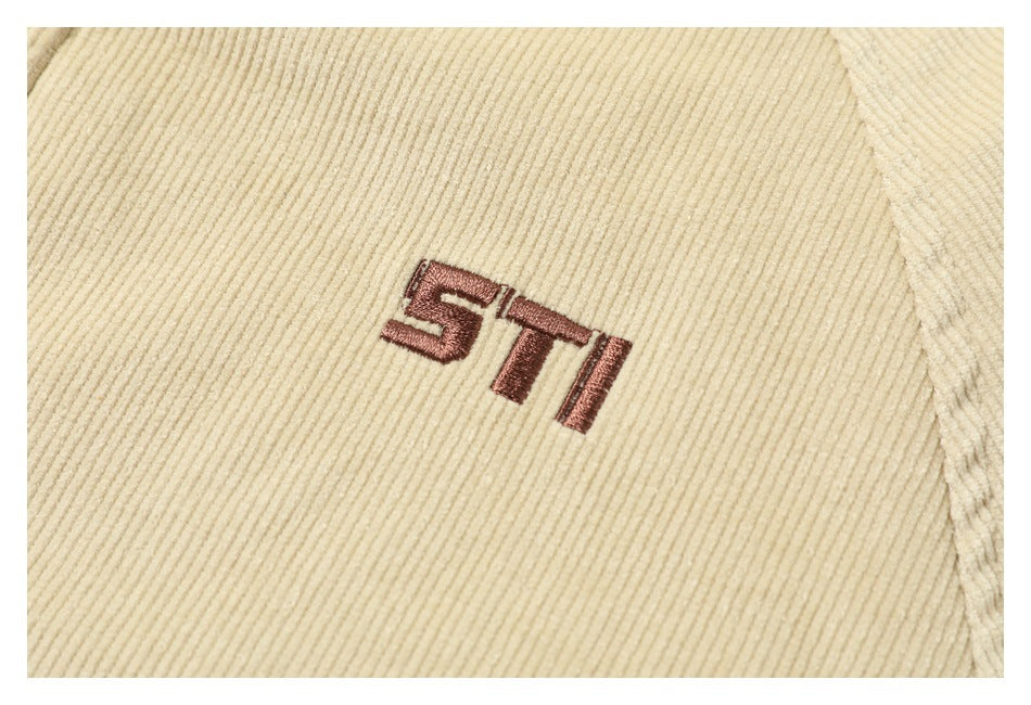 Close-up of a small brown embroidered ST design on beige ribbed fabric.