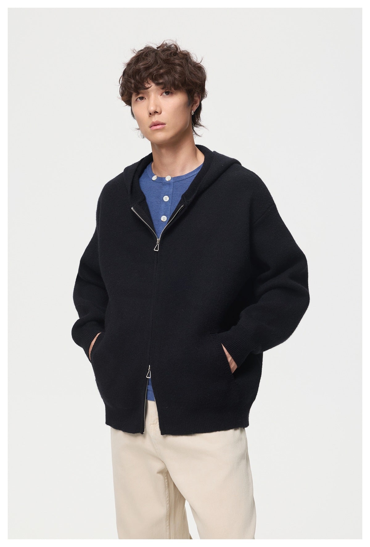Model wearing a black zip-front hooded cardigan over a blue button-neck shirt.
