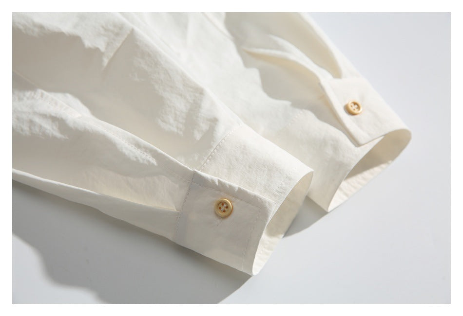Close-up of a white shirt cuff with a tan button and matching button placket.