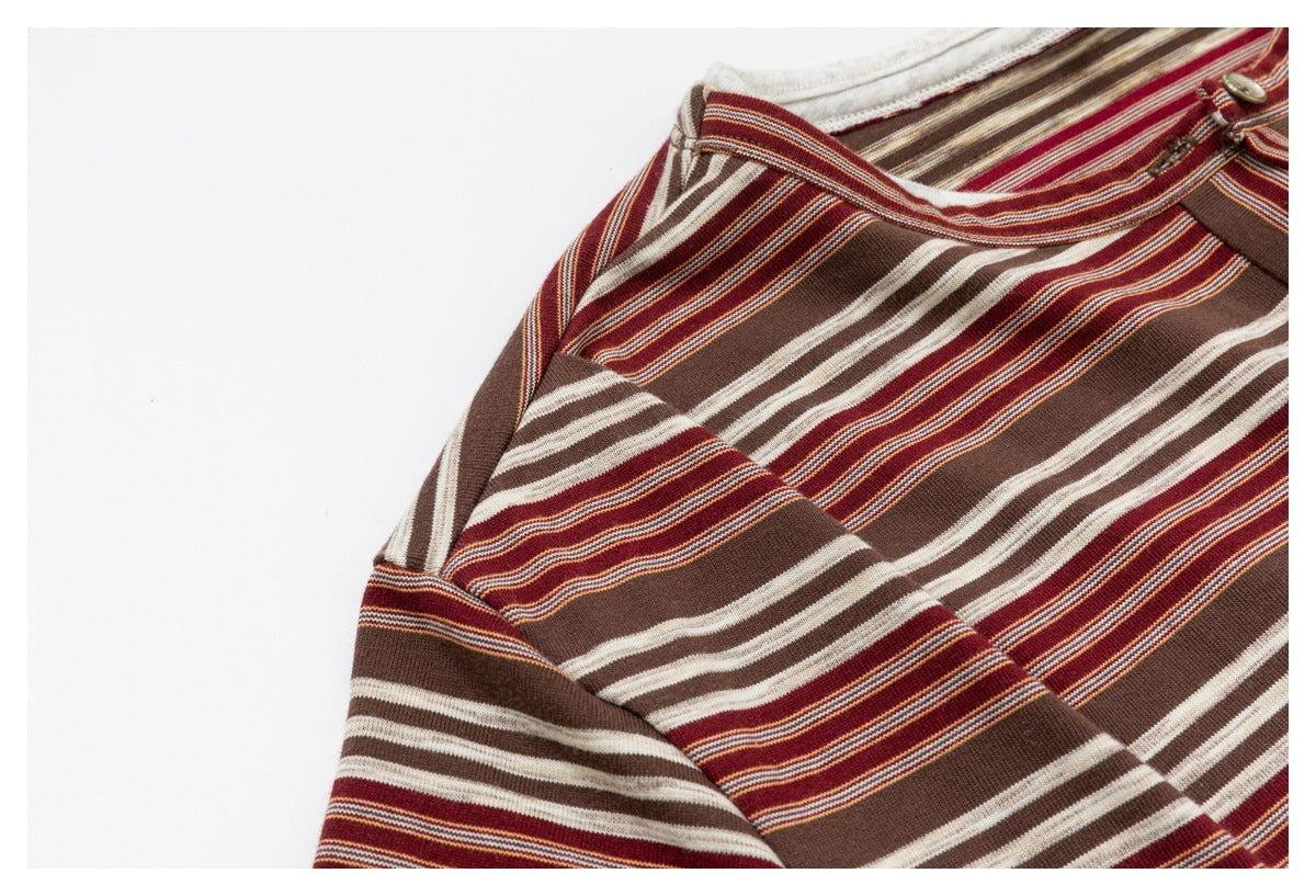 Close-up of the shoulder and neckline of a brown, burgundy, and cream striped top with a partial button closure.