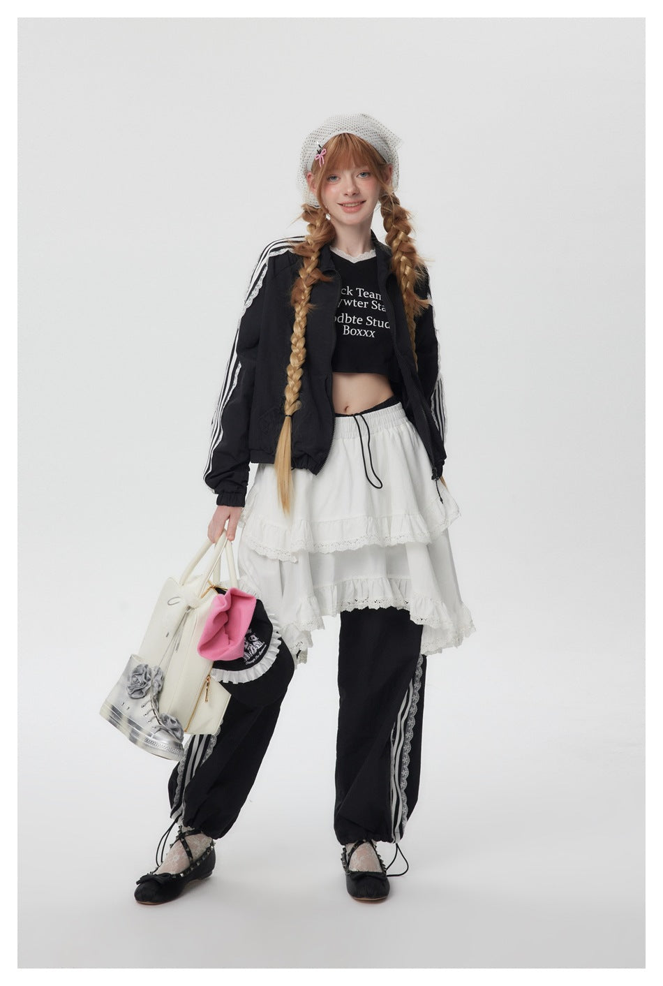 Model wearing the black striped lace-trim cropped jacket open over a black crop top, white tiered skirt and black pants