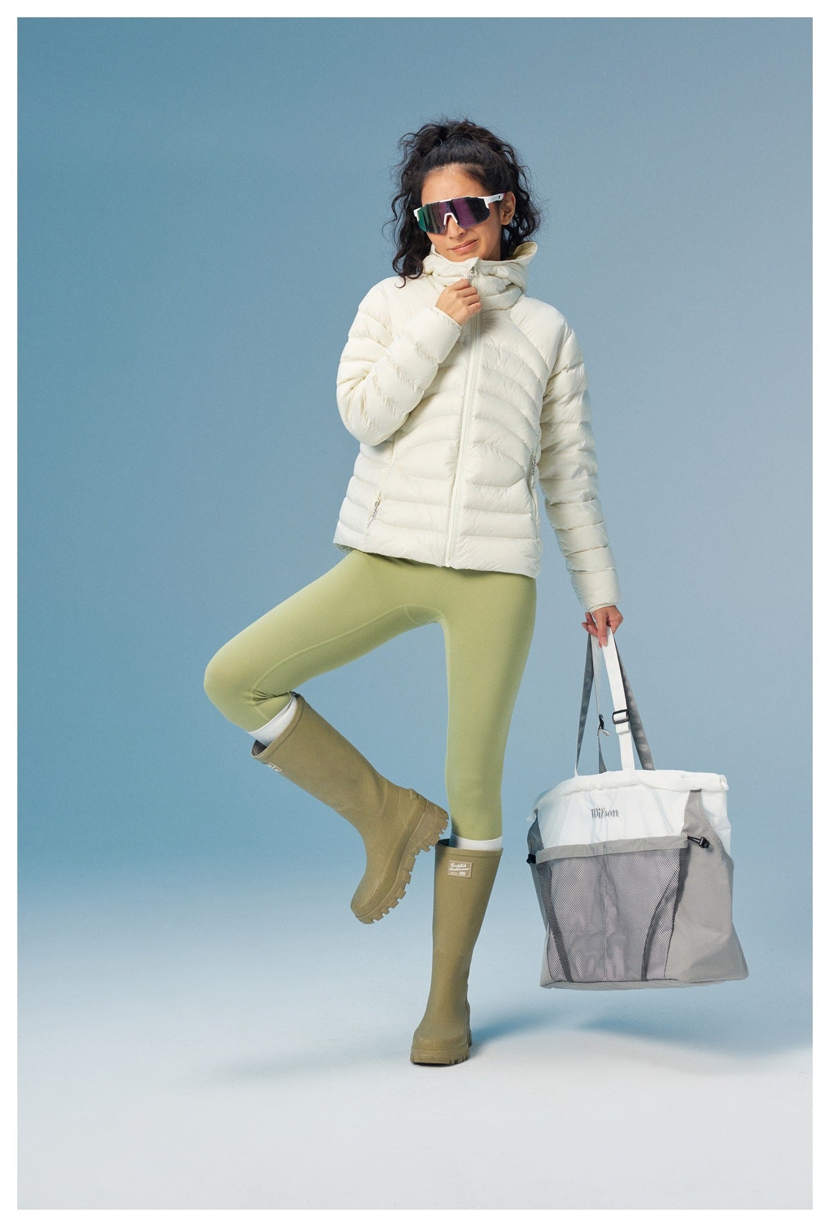 Full-length model wearing a white quilted hooded jacket, pale green leggings, and olive boots.