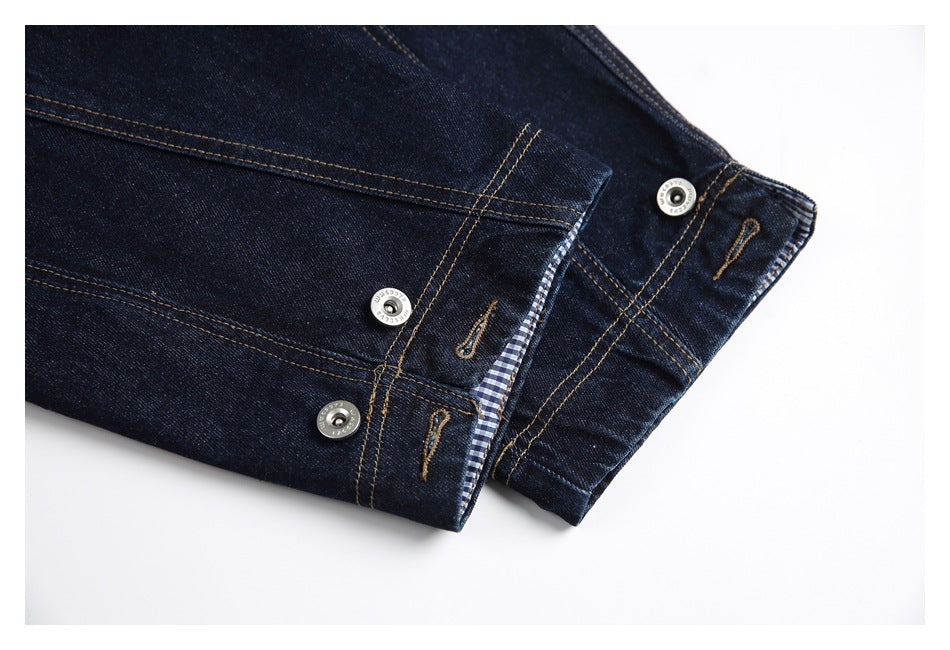 Close-up of dark denim cuffs with tan stitching, metal snaps and a glimpse of blue checked lining.