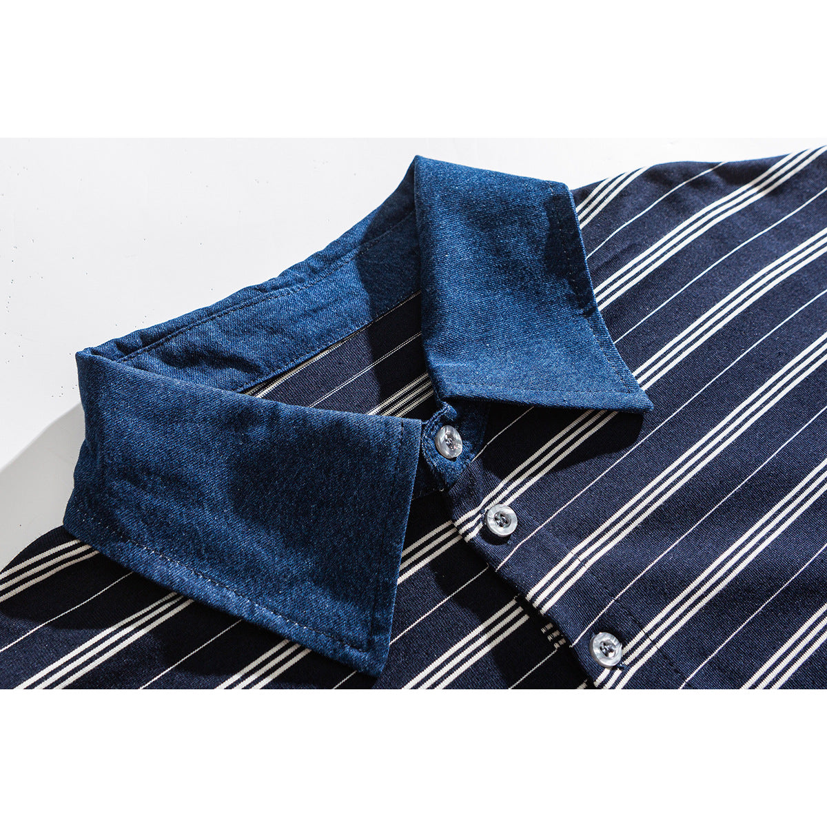 Close-up of a navy shirt with white stripes, a blue collar and silver buttons.