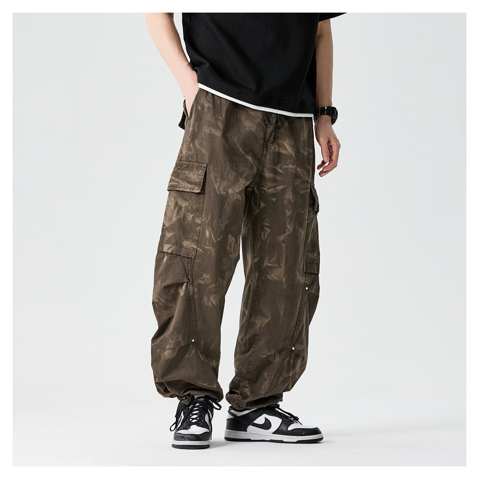 Model wearing coffee brown tie-dye wide-leg cargo pants with a black tee and black-and-white sneakers, front view