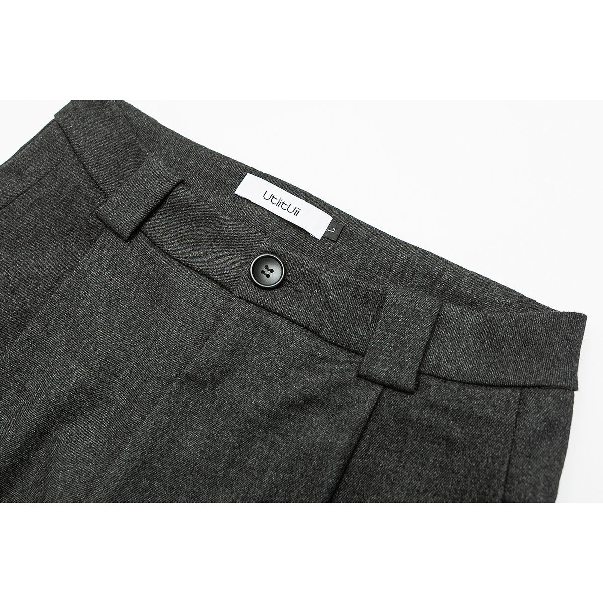 Close-up of charcoal gray trousers showing the waistband, belt loops, button, and sewn-in brand label.