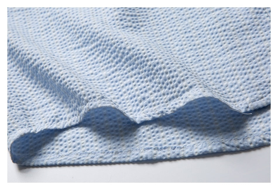 Close-up of the pale blue shirt's stitched hem and raised textured fabric.