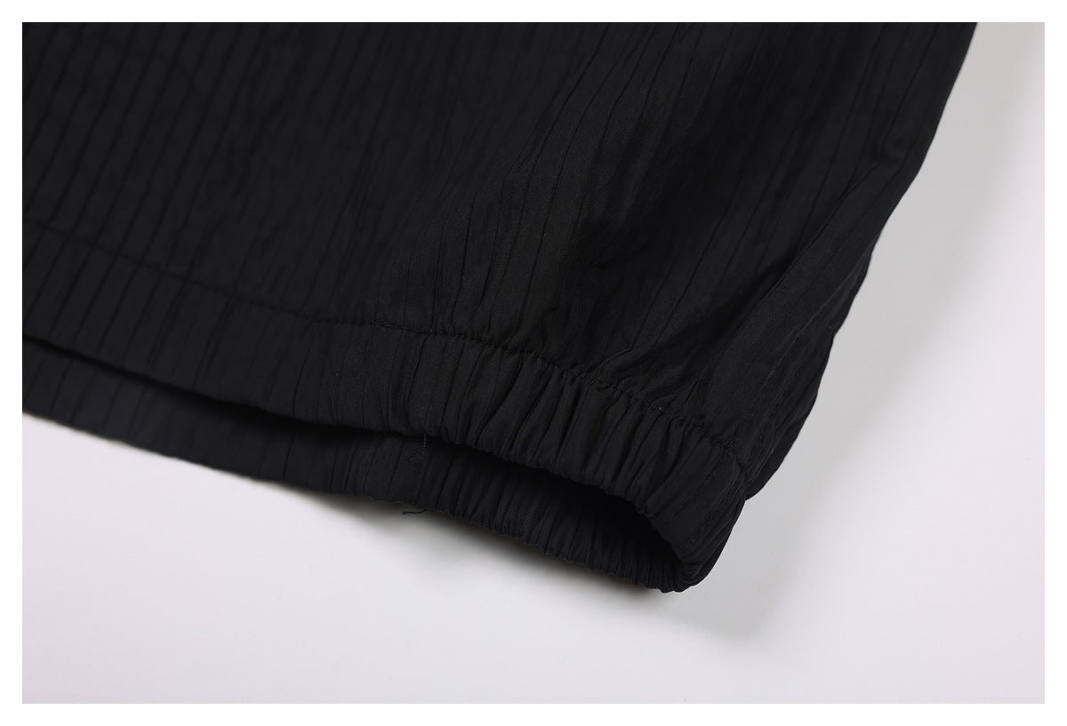 Close-up of the gathered elastic cuff and fine vertical texture on black trousers.