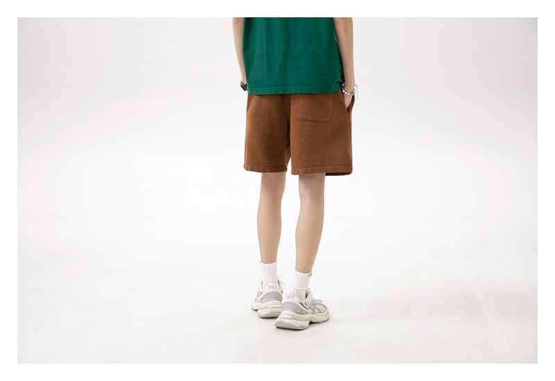 Back view of a model wearing brown shorts, showing a rear patch pocket.