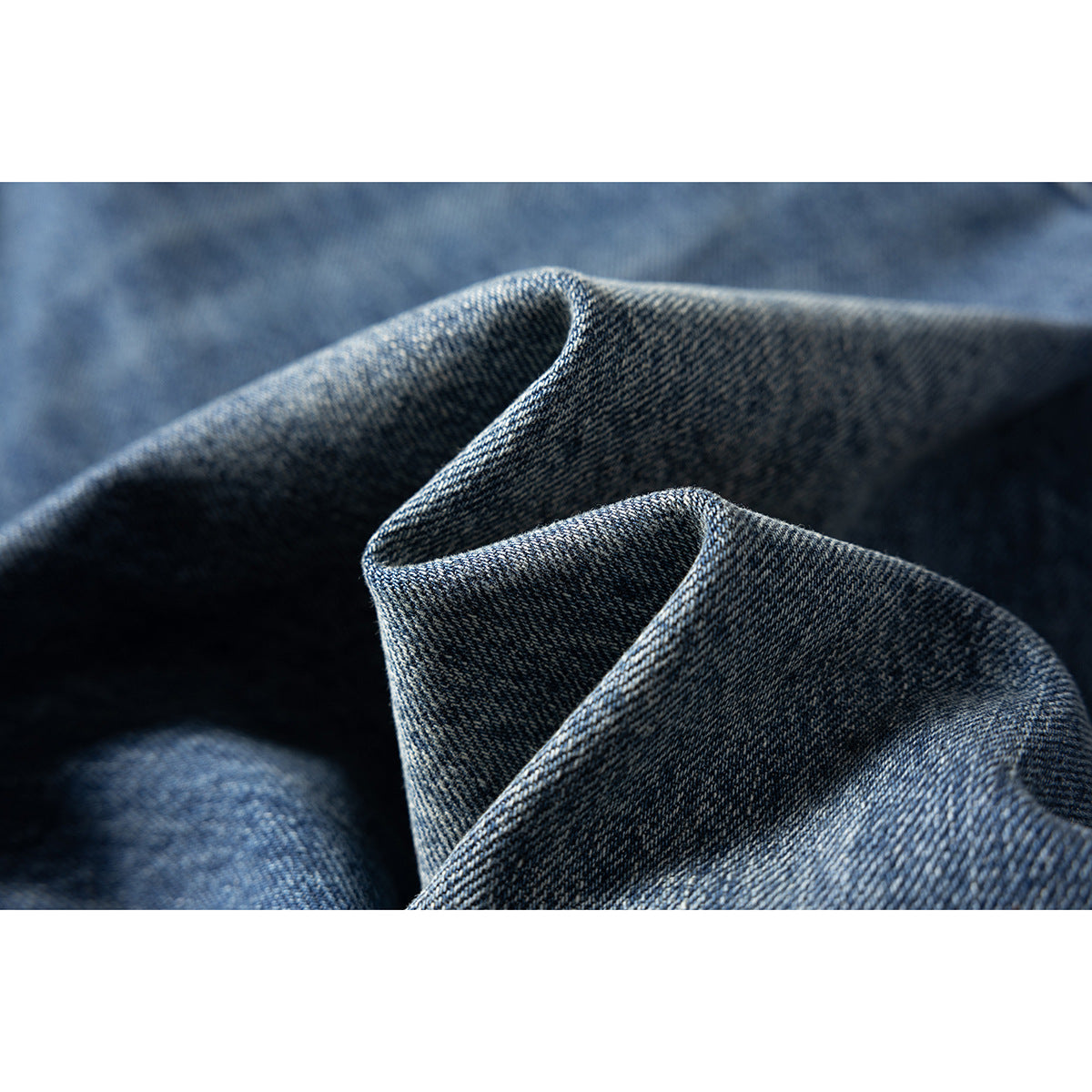 Macro view of folded blue denim showing its diagonal weave and texture.