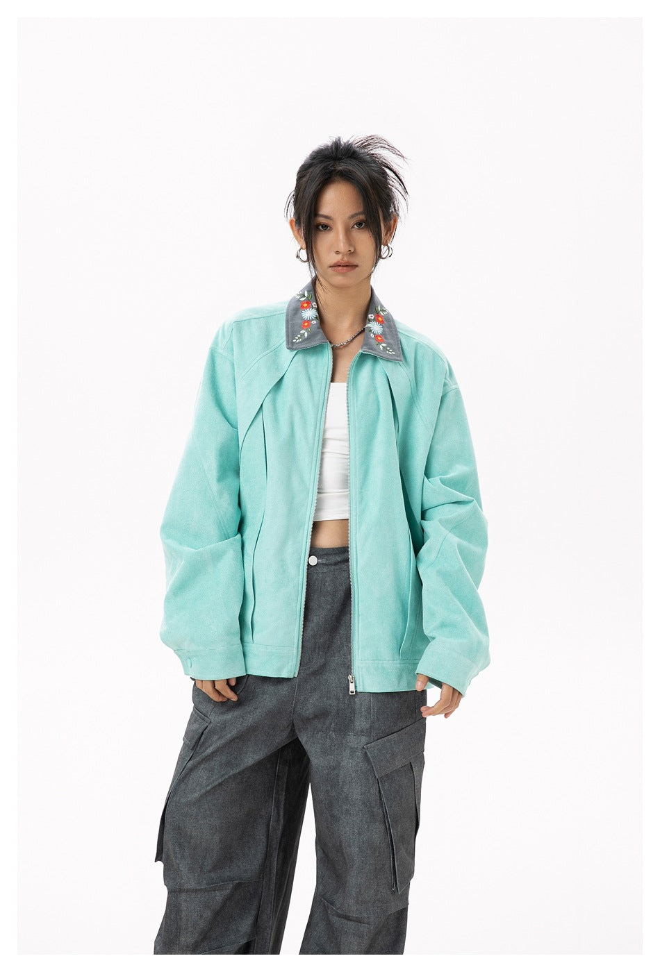 Front view of a model wearing a mint zip jacket with a gray floral collar and charcoal cargo pants.