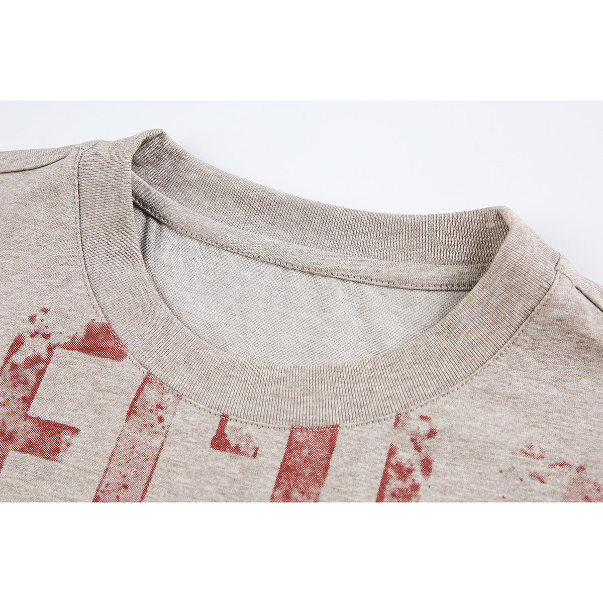 Close-up of a beige heather T-shirt's ribbed crew neck and distressed red chest print.