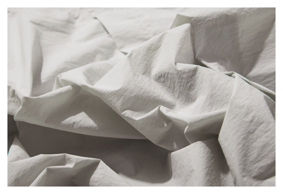 Close-up of pale gray garment fabric folded into loose ridges.