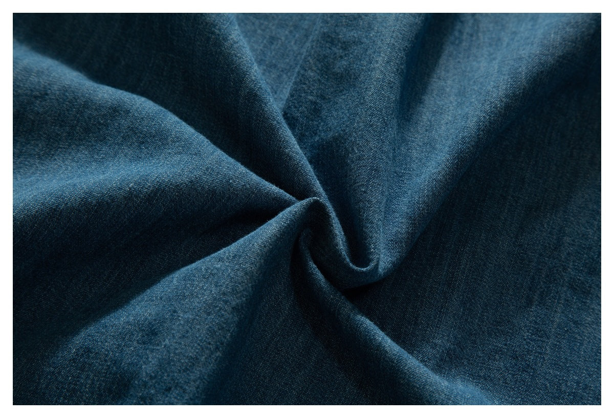 Close-up of blue denim fabric gathered into soft folds, showing its surface and texture.