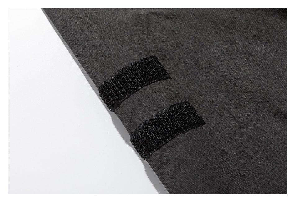 Close-up of two black hook-and-loop tabs on the edge of a dark charcoal garment.