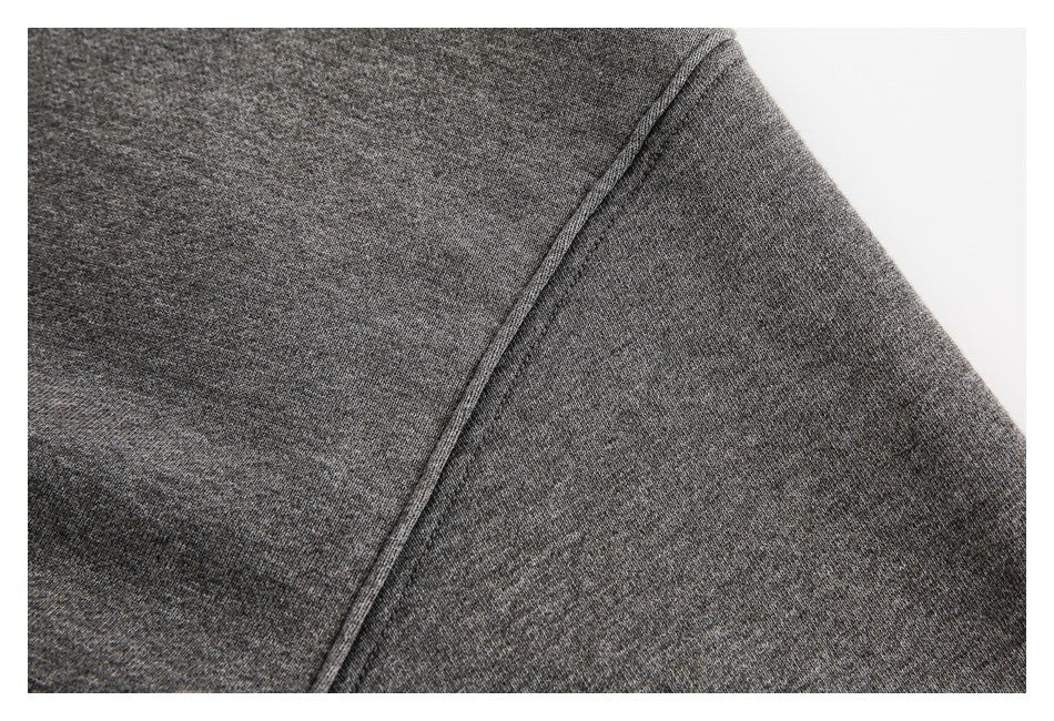 Close-up of a stitched shoulder and sleeve seam on charcoal gray sweatshirt fabric.