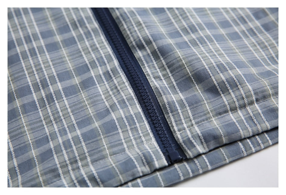 Close-up of the navy front zipper and hem on the blue-gray plaid jacket.