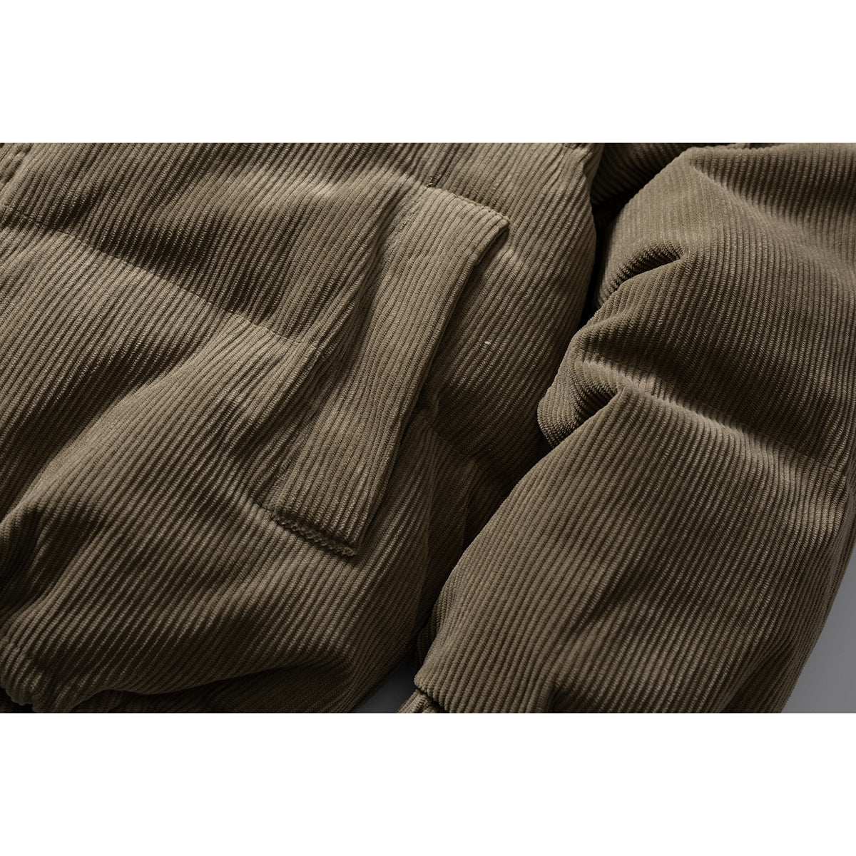 Close-up of the olive-brown jacket’s ribbed pocket flap and sleeve.